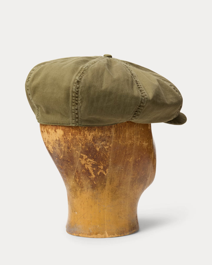 Green cap on a wooden mannequin head against a white background