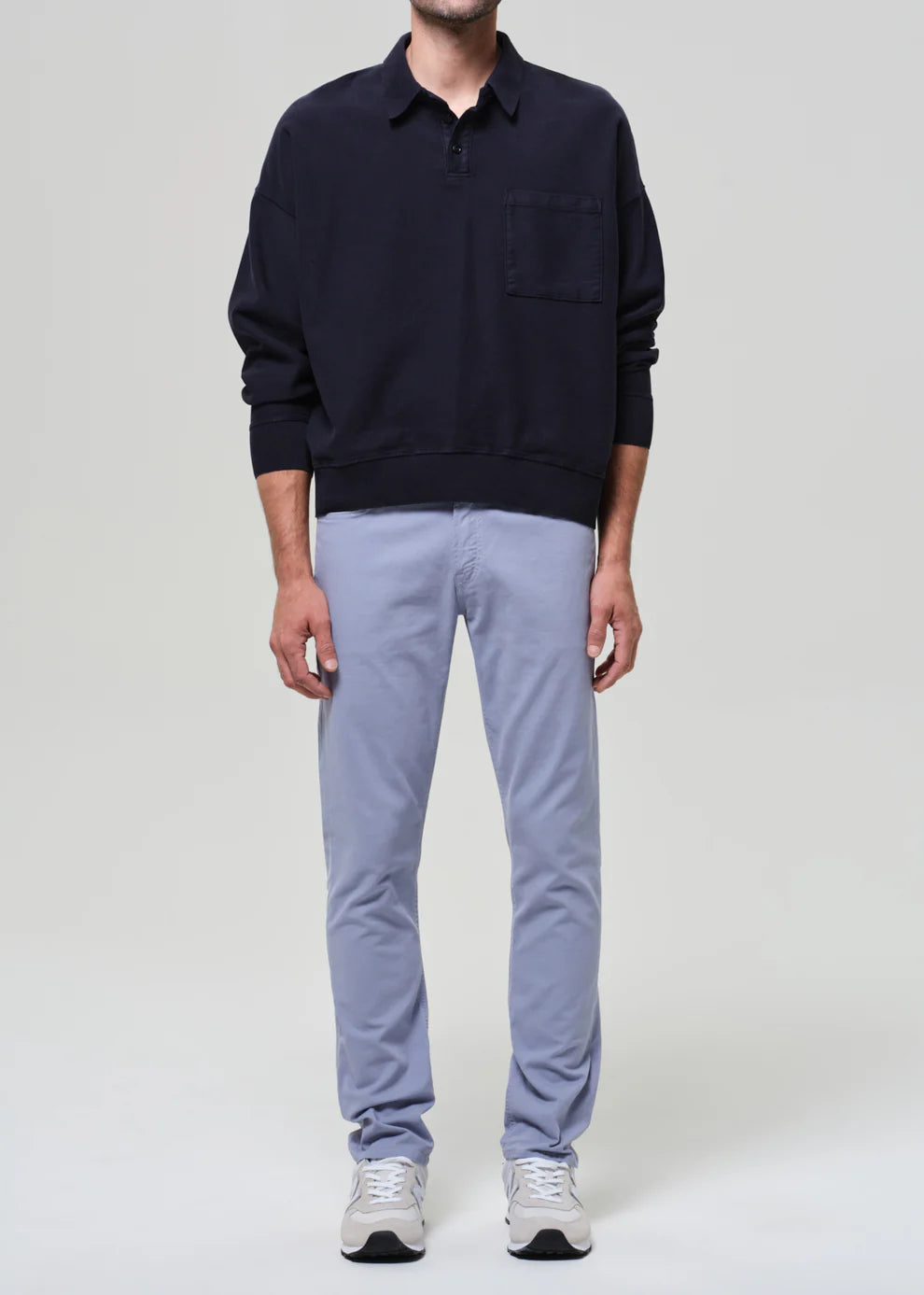 Person wearing a navy sweater and light gray pants on a white background