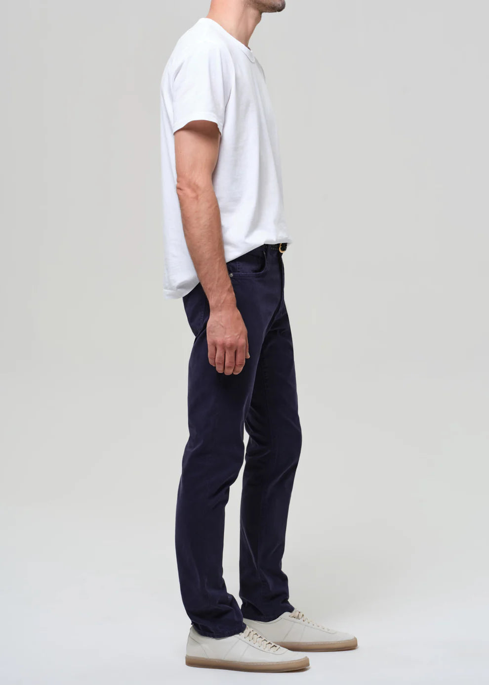 Person wearing a white t-shirt and navy pants on a plain background