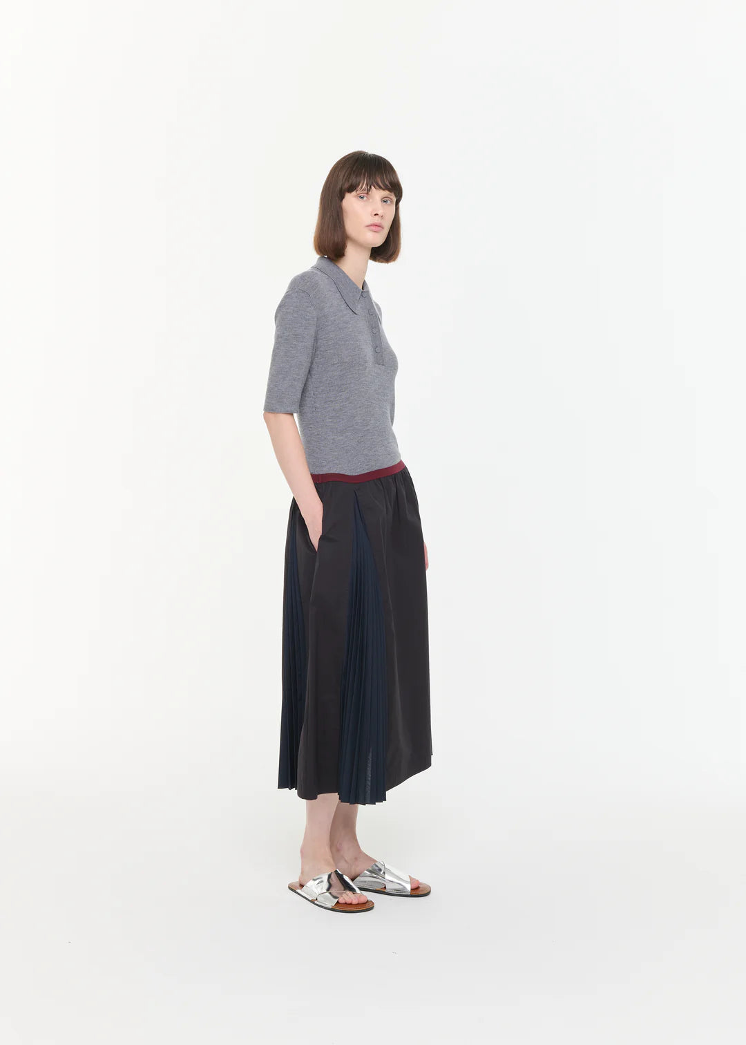 Woman wearing a gray sweater and black skirt on a white background