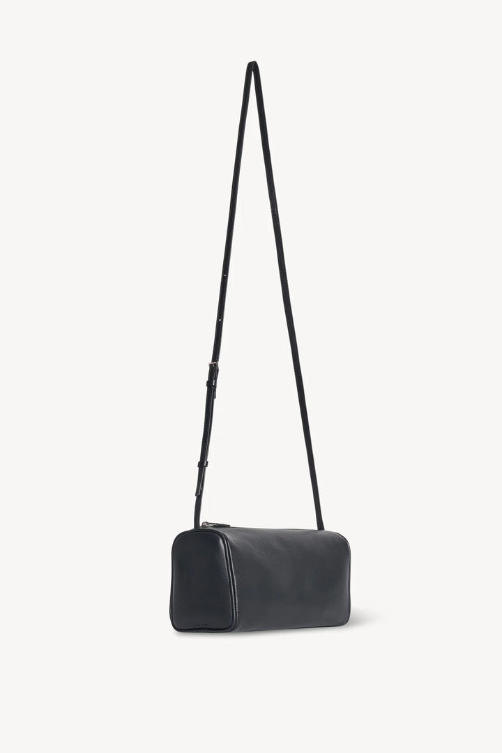 Black handbag with a strap on a light gray background