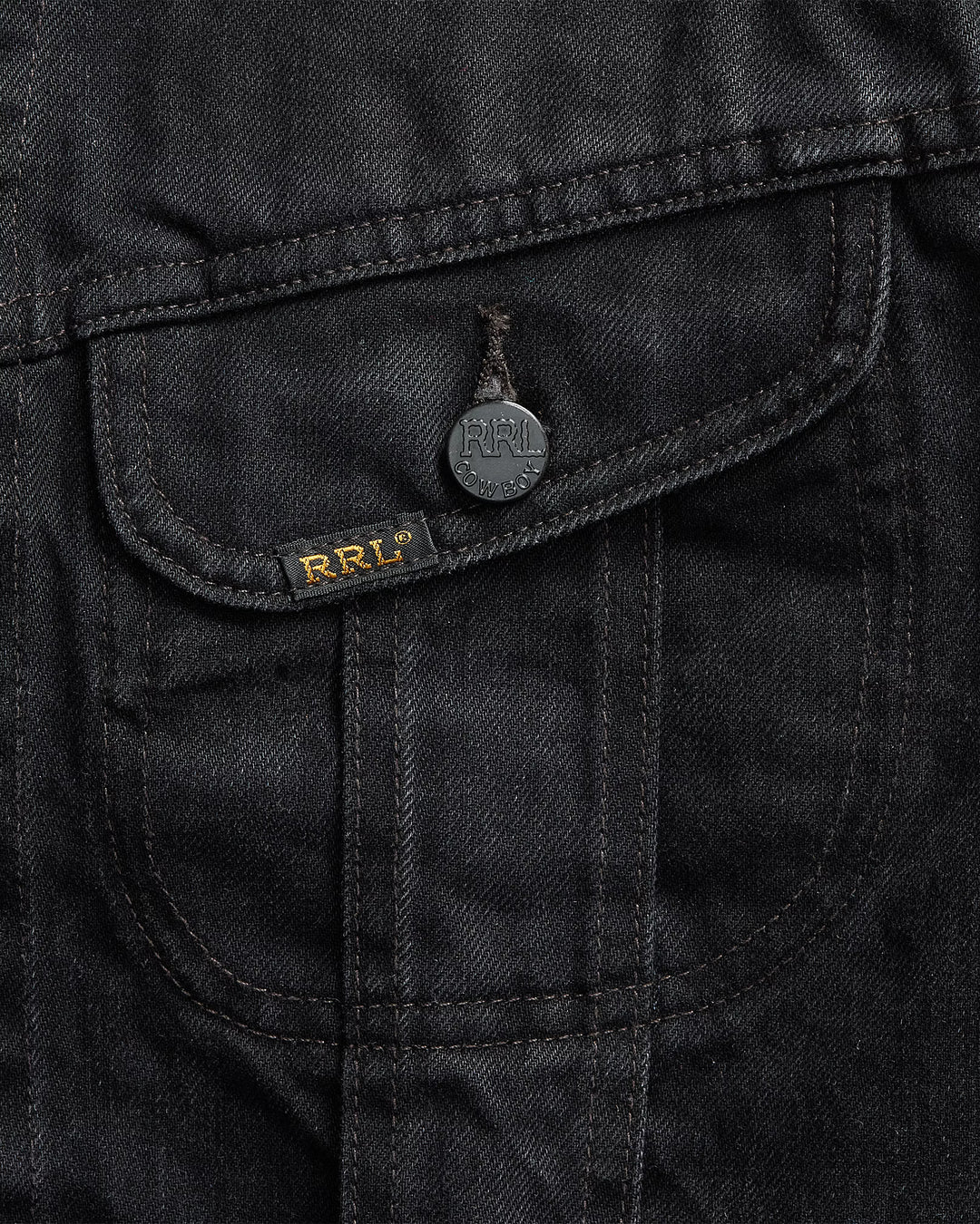 Close-up of a black jacket pocket with a brand logo on a dark background