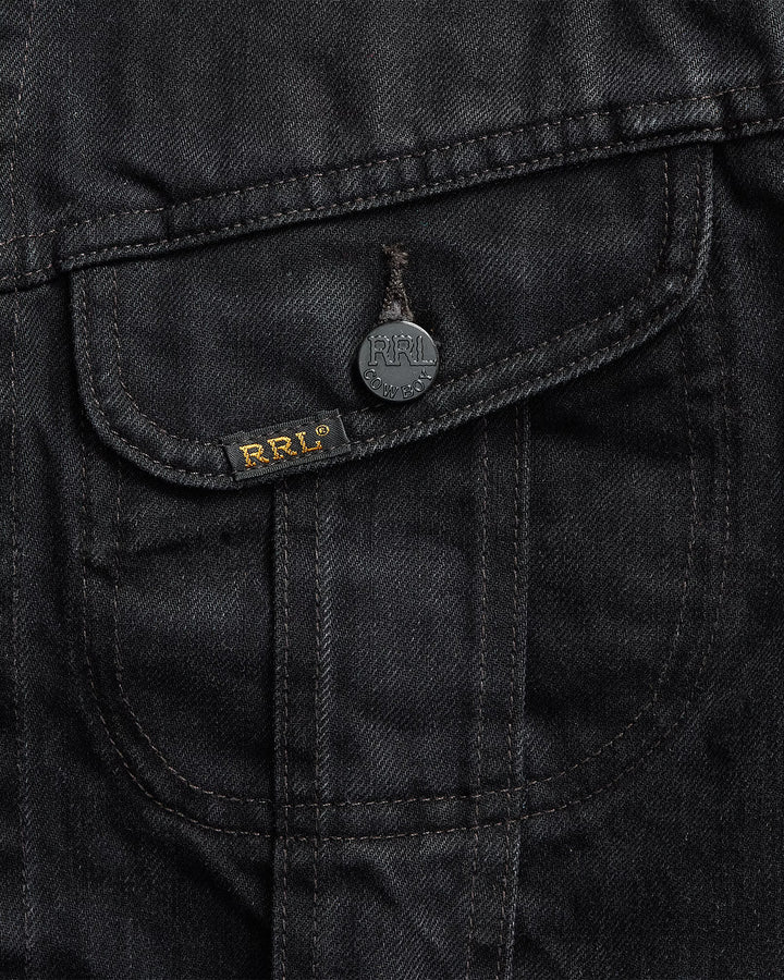 Close-up of a black jacket pocket with a brand logo on a dark background