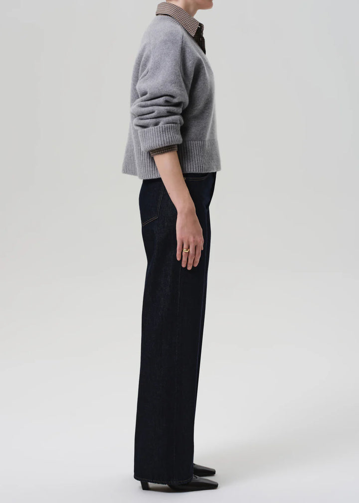 Person wearing a gray sweater and black pants on a white background