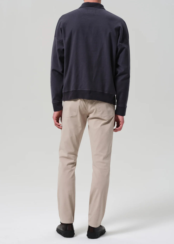 Person wearing a navy sweater and beige pants on a white background
