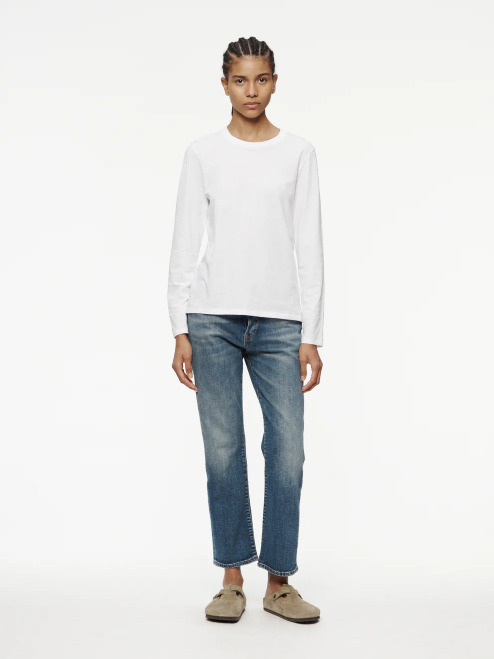 Person wearing a white long-sleeve shirt and blue jeans on a white background