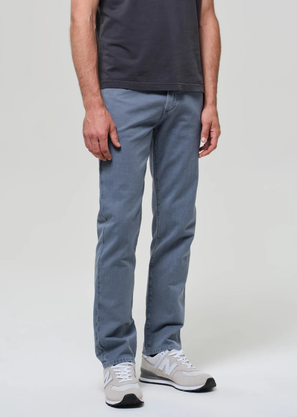Person wearing blue jeans and a dark shirt on a plain background