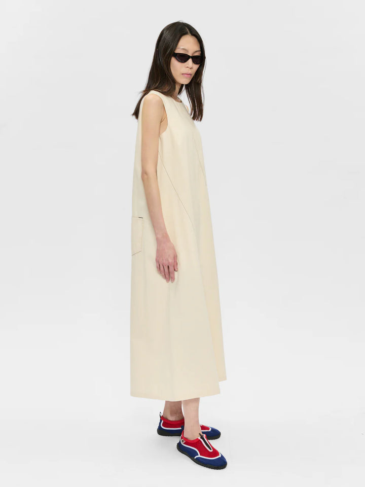 Woman wearing a beige sleeveless dress on a white background