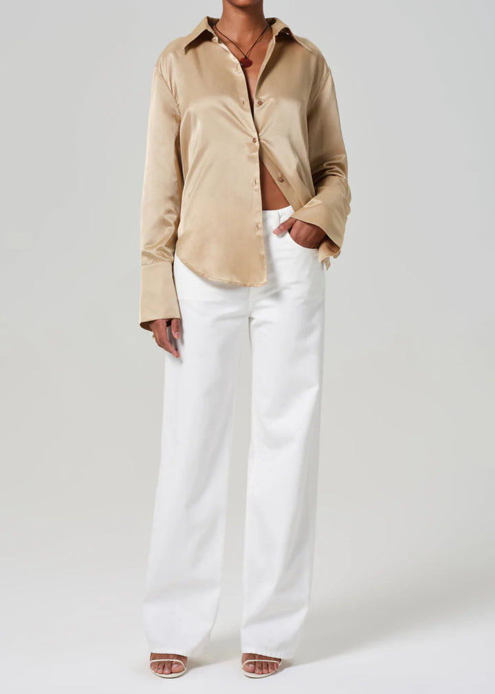 Person wearing a beige shirt and white pants on a plain background