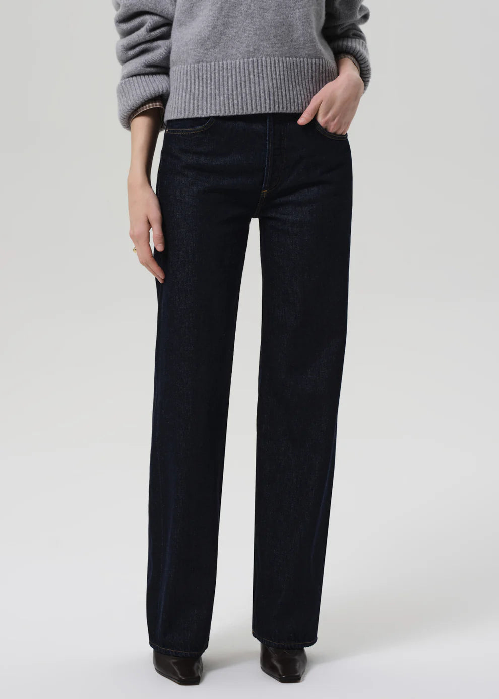 Person wearing black pants and a gray sweater on a white background