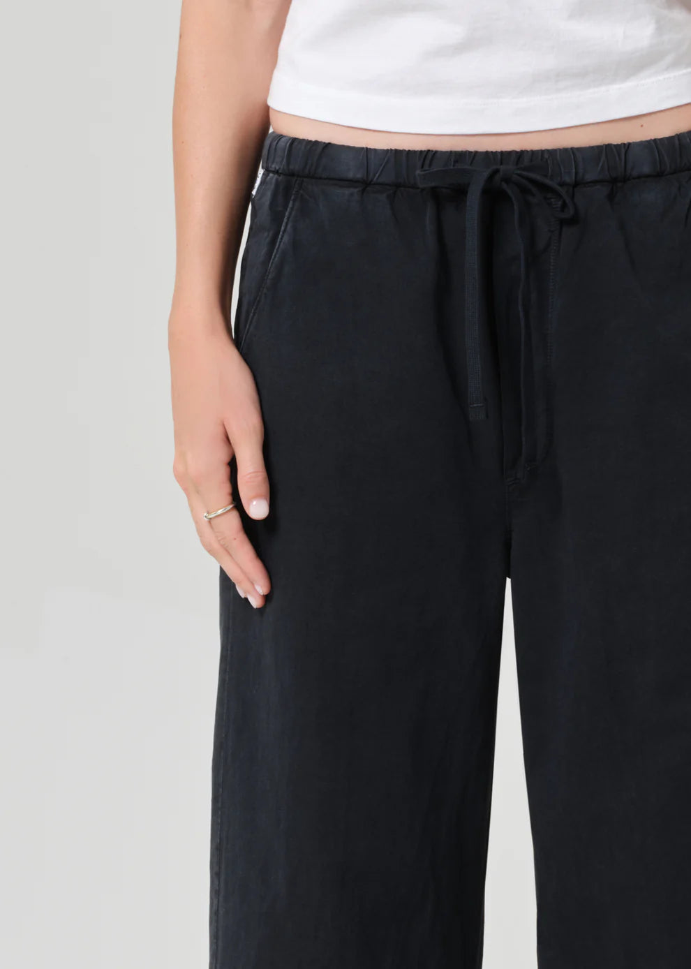 Black pants with a drawstring waist on a plain background