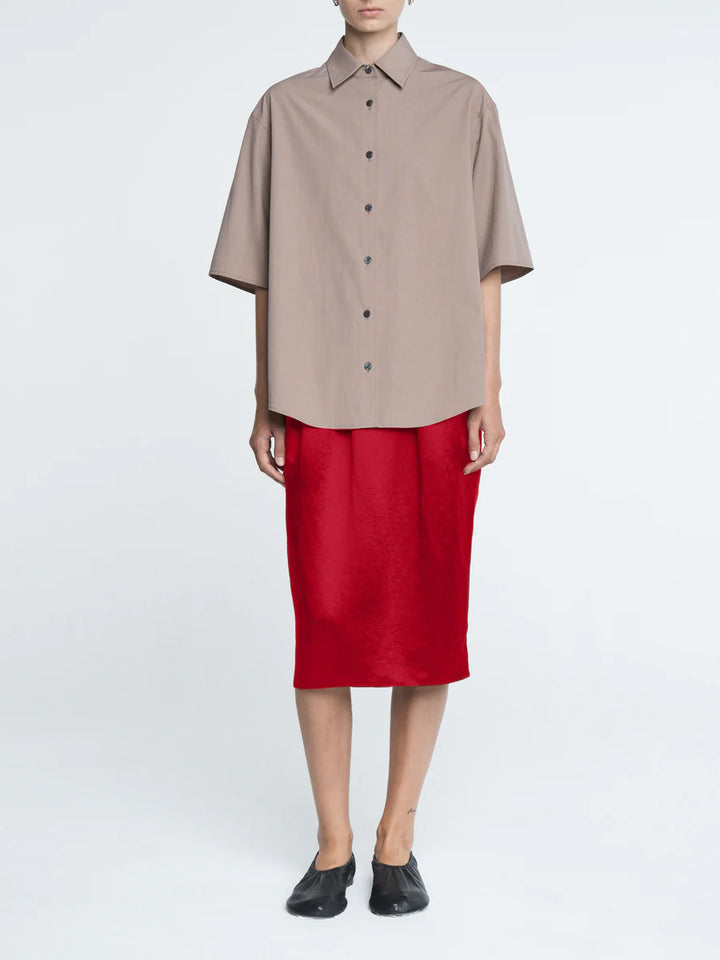 Person wearing a beige shirt and red skirt on a white background