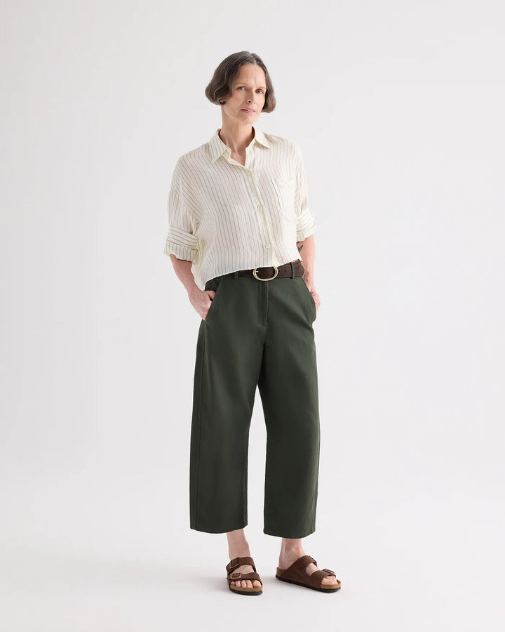 Person wearing a white button-up shirt and green pants on a plain background