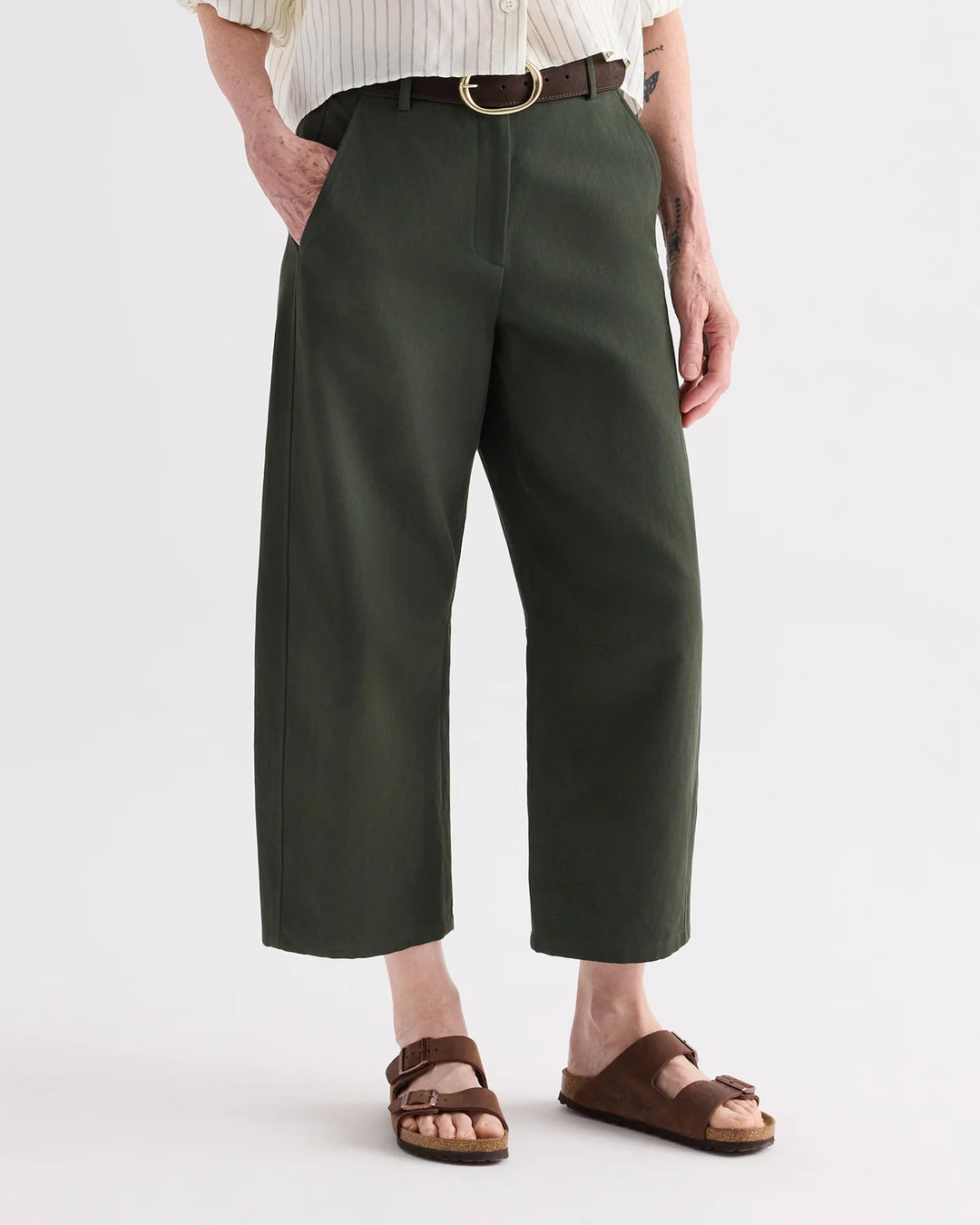 Person wearing green pants and brown sandals on a white background