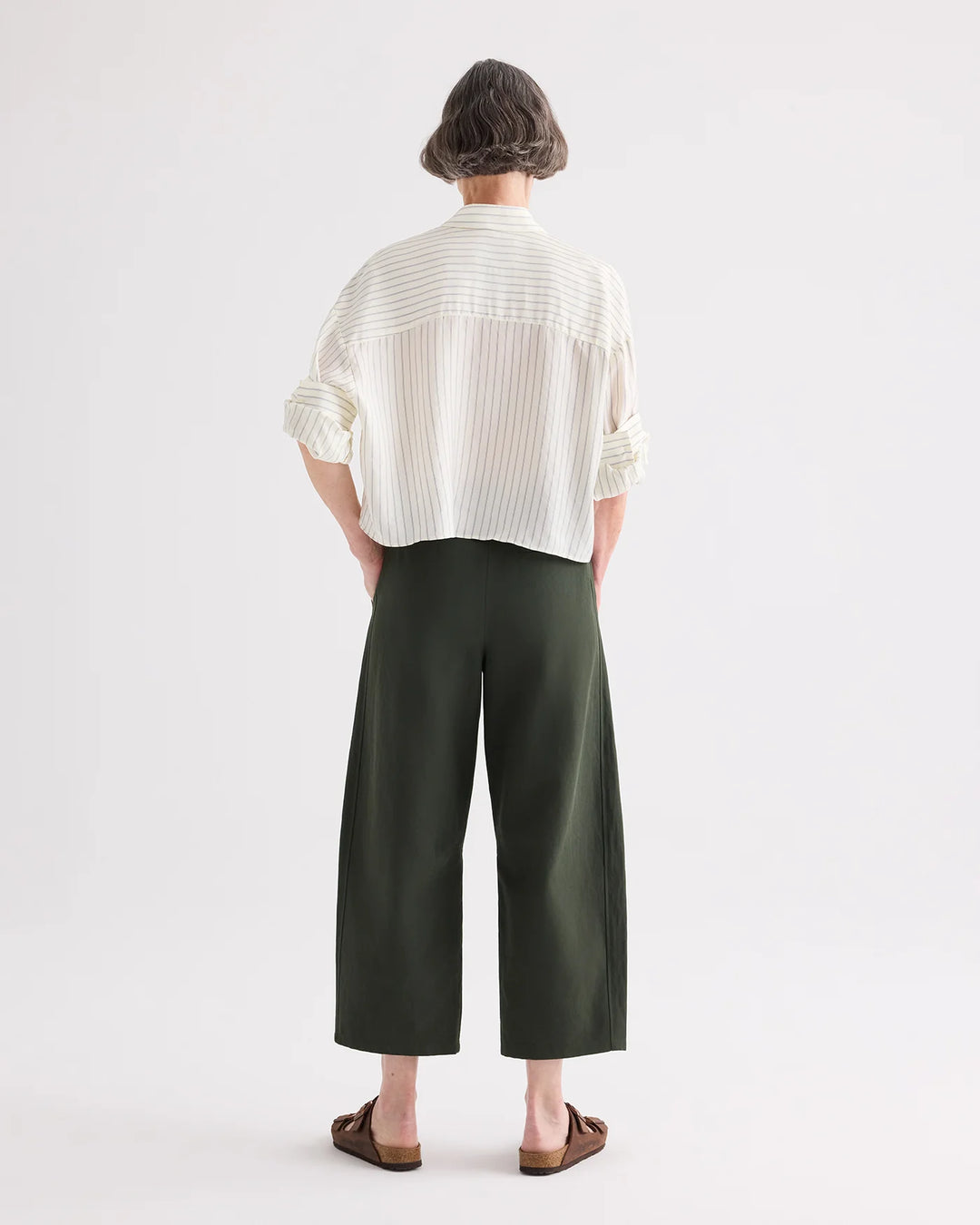 Person wearing a white shirt and green pants on a white background