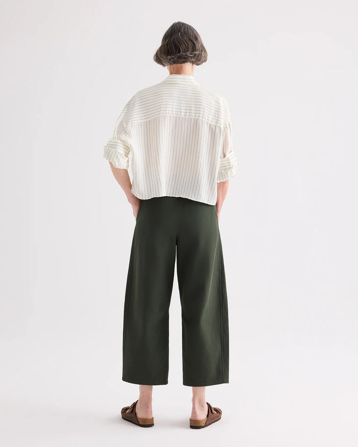 Person wearing a white shirt and green pants on a white background