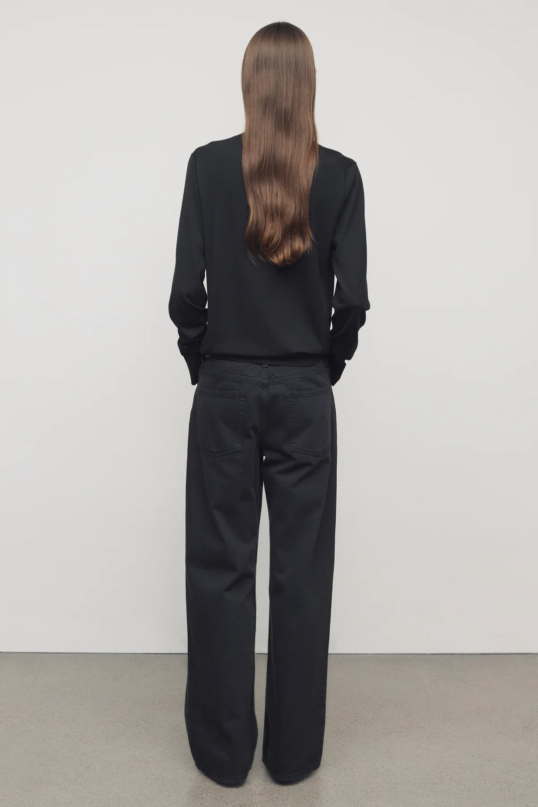 Person wearing a black outfit standing against a plain white background