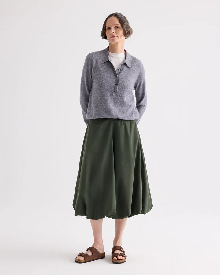 Woman wearing a gray sweater and green skirt on a white background