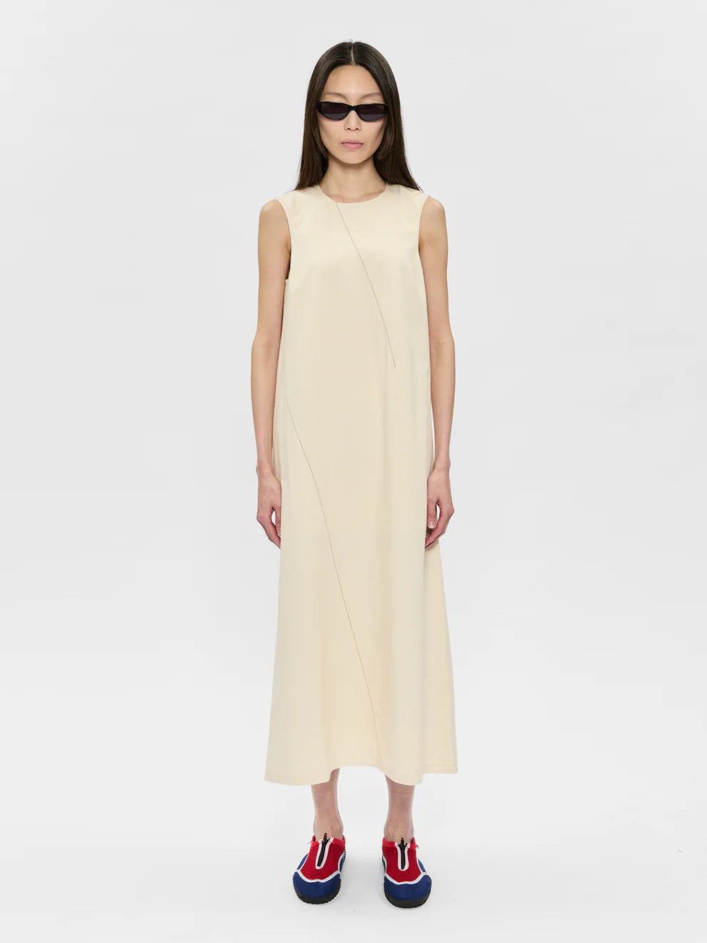 Woman wearing a beige sleeveless dress on a white background