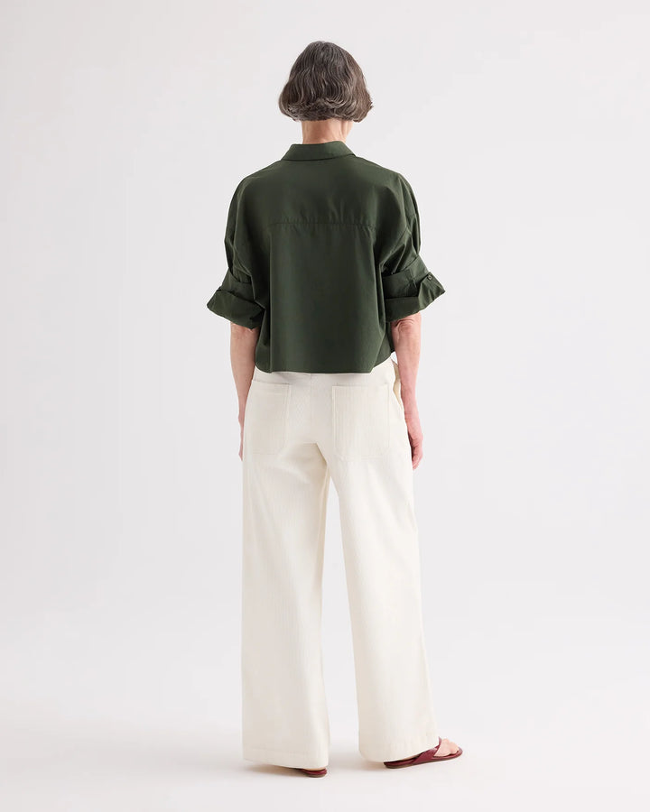 Person wearing a green shirt and white pants on a white background