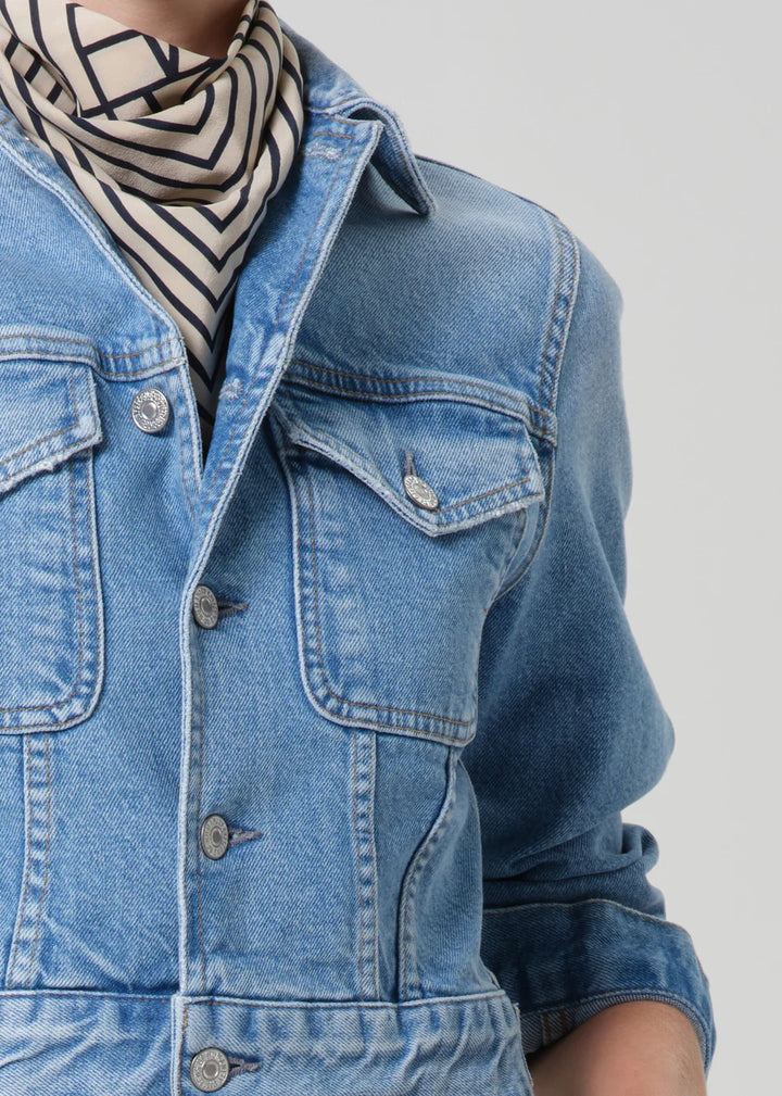 Person wearing a blue denim jacket with a striped scarf