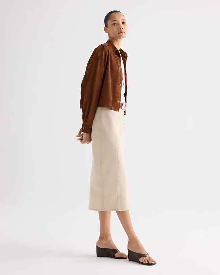 Woman wearing a brown shirt and beige skirt on a white background