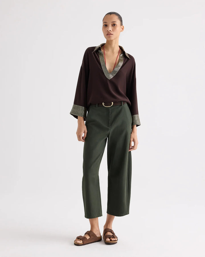 Woman wearing a brown shirt and green pants on a white background