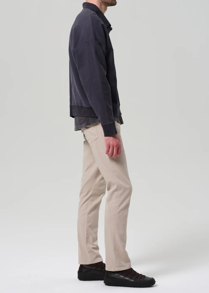 Person wearing a dark shirt and beige pants on a white background