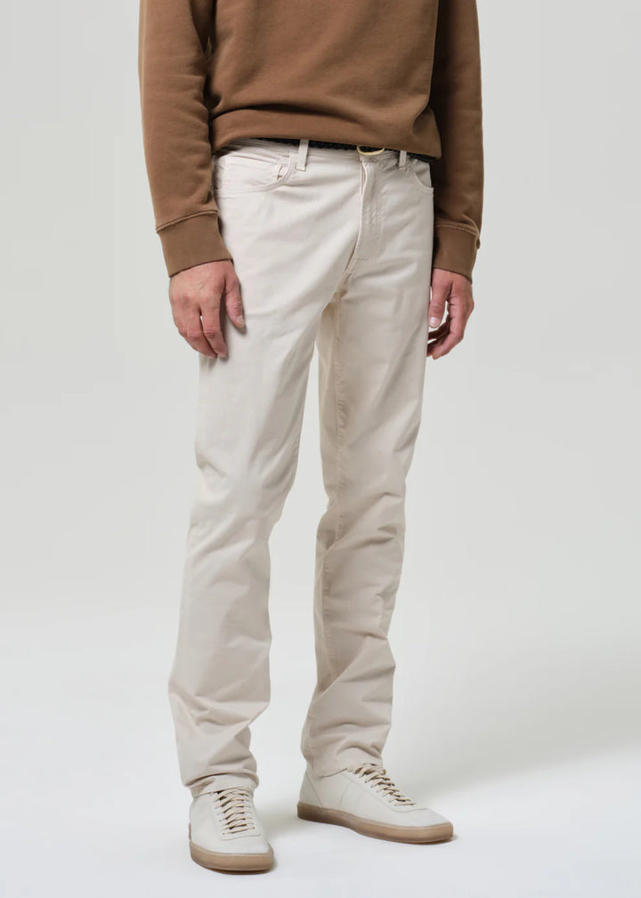 Person wearing a brown sweater and beige pants on a white background