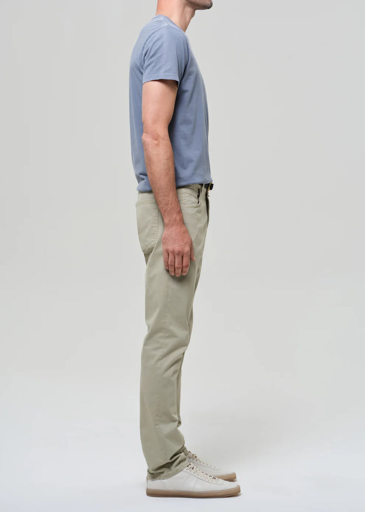 Person wearing a light blue t-shirt and beige pants on a plain background