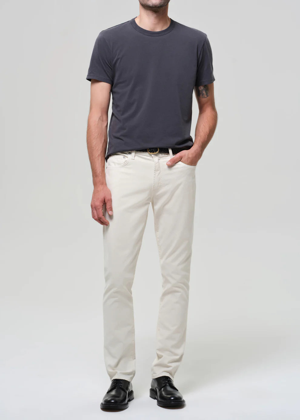 Person wearing a dark gray t-shirt and white pants on a plain background