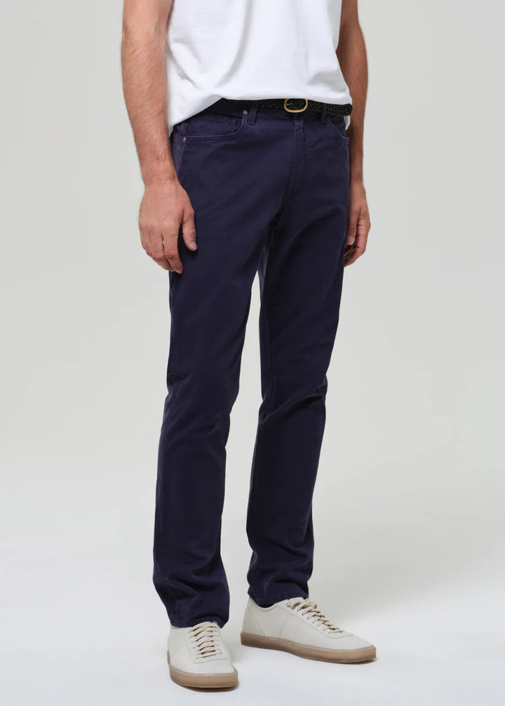 Person wearing navy pants and white shoes on a plain background