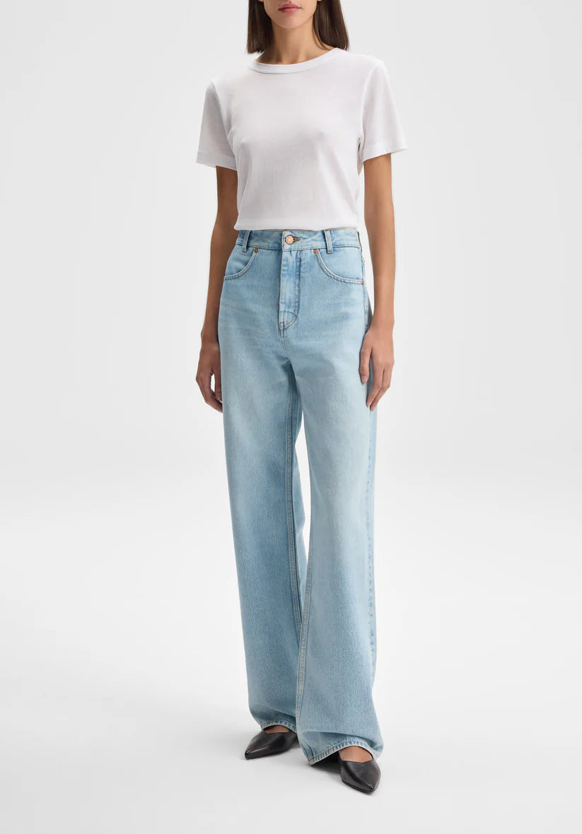 Person wearing light blue jeans and a white top on a white background