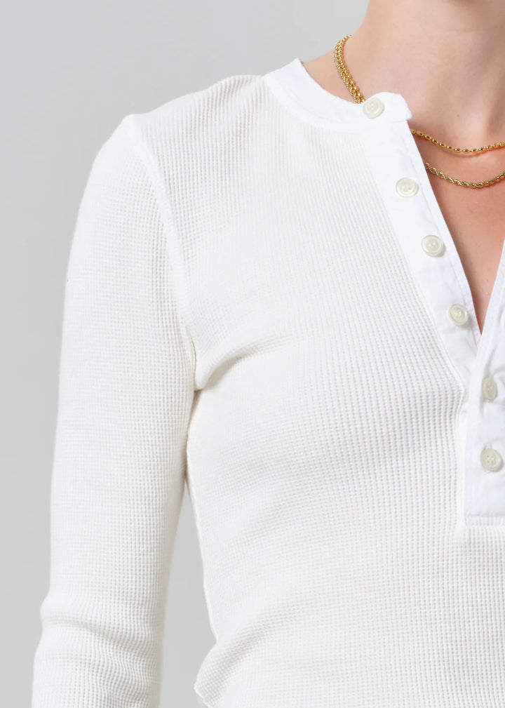White ribbed sweater with buttons on a gray background