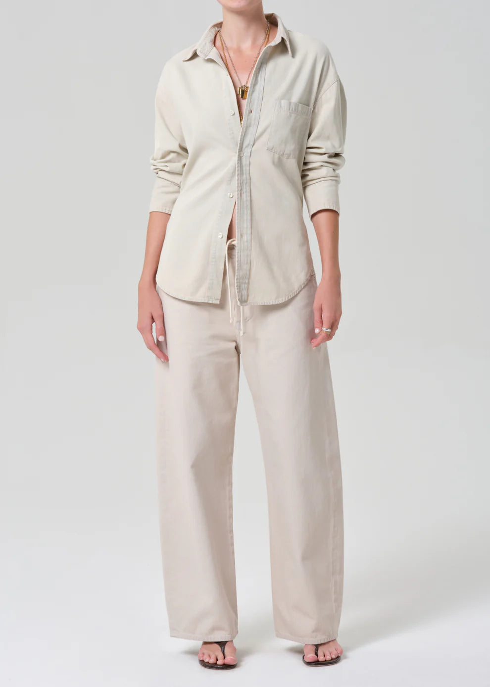 Person wearing a beige shirt and pants set on a white background