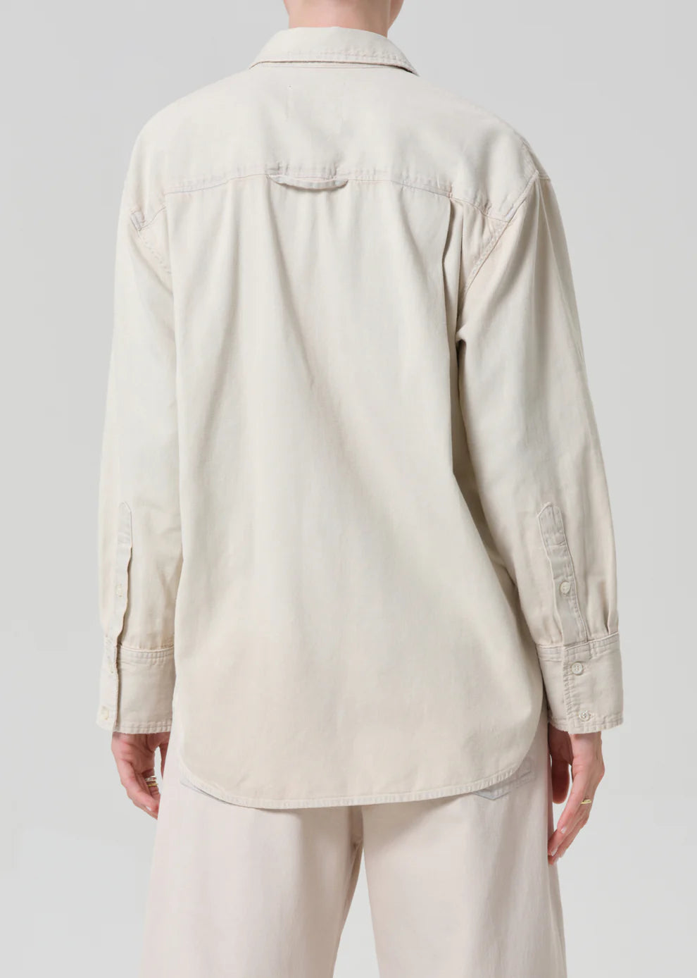 Person wearing a beige shirt and pants on a plain background