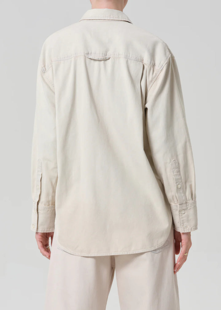 Person wearing a beige shirt and pants on a plain background