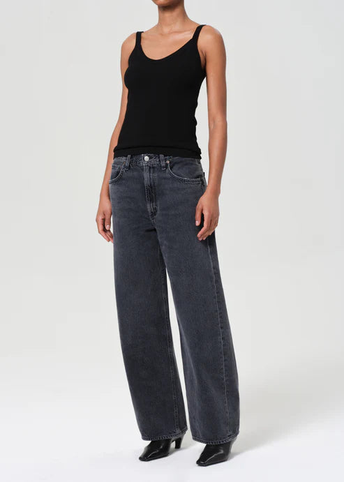 Person wearing a black tank top and blue jeans on a white background