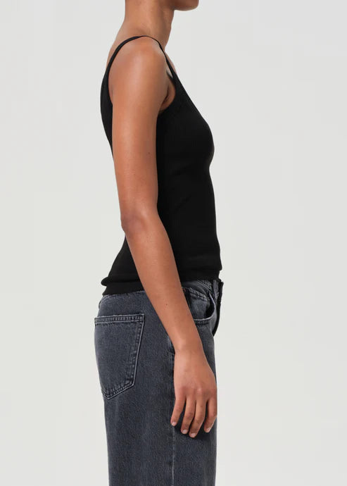 Person wearing a black tank top and gray jeans on a light gray background