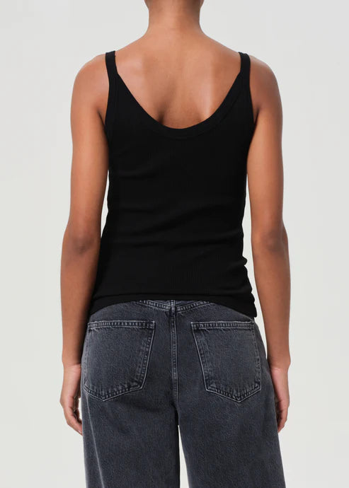 Person wearing a black tank top and dark jeans on a plain background