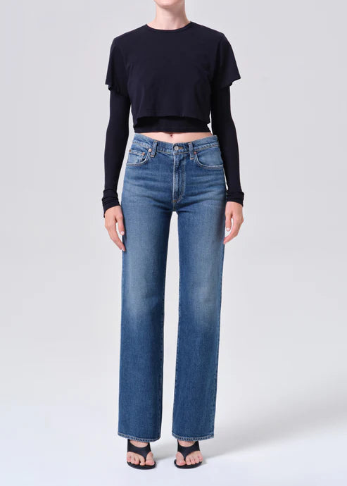 Person wearing a black crop top and blue jeans on a white background