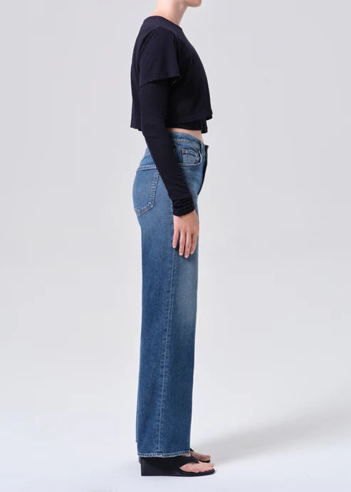Person wearing blue jeans and a black cropped top on a white background