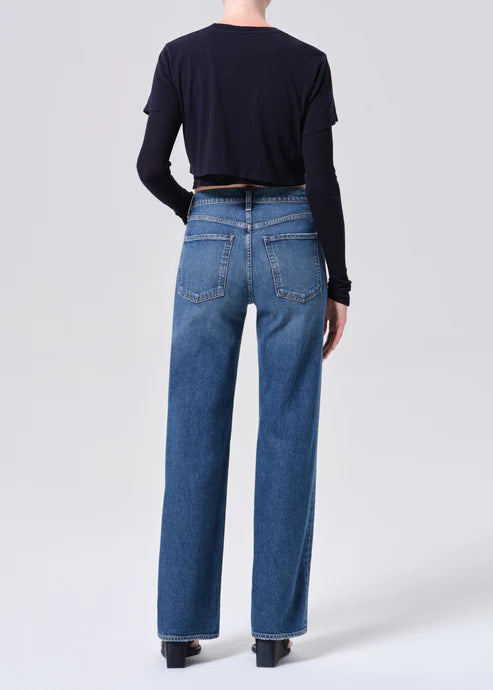 Person wearing blue jeans and a black top on a white background