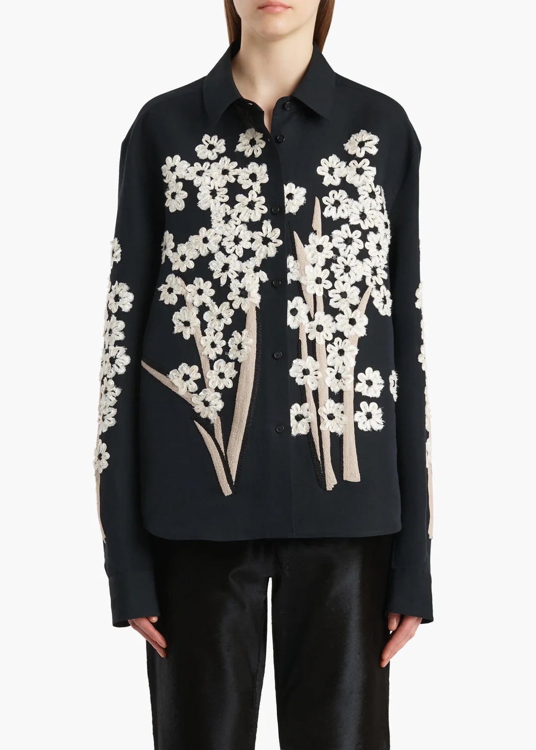 Black shirt with white floral patterns worn by a person on a white background