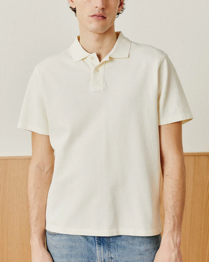 Person wearing a plain white polo shirt against a neutral background