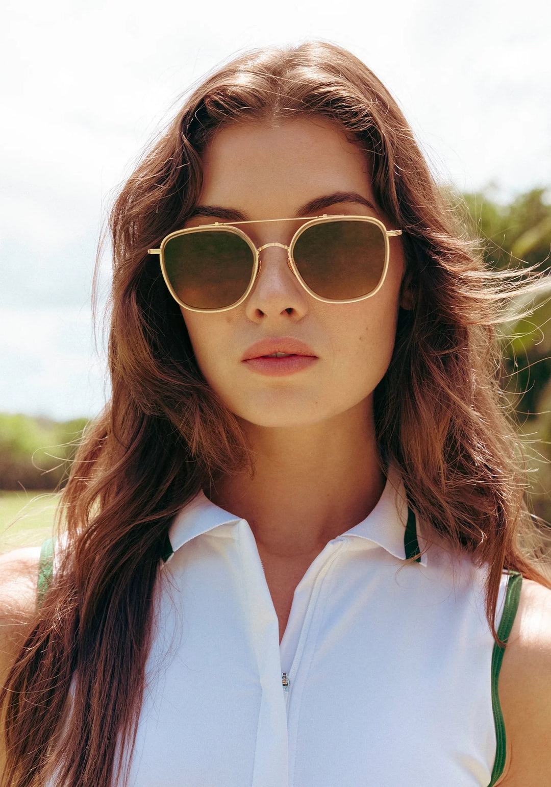 Woman wearing gold sunglasses with a blurred natural background