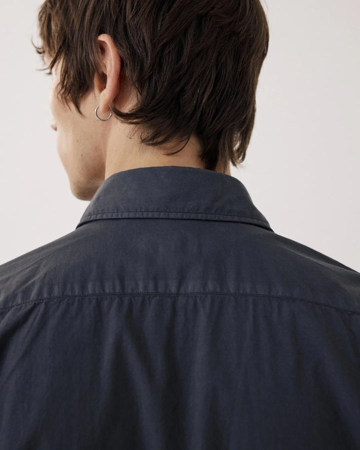 Person wearing a dark blue shirt against a plain background