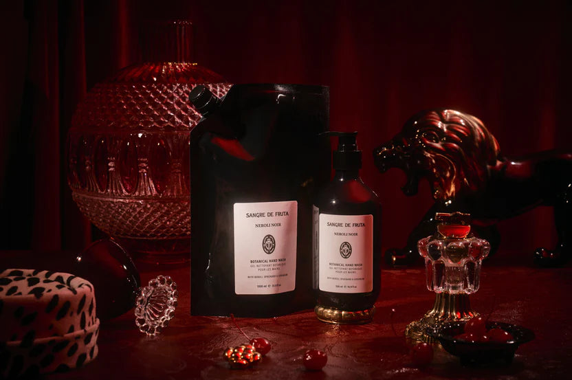 Two black bottles with labels on a dark surface, surrounded by decorative items.