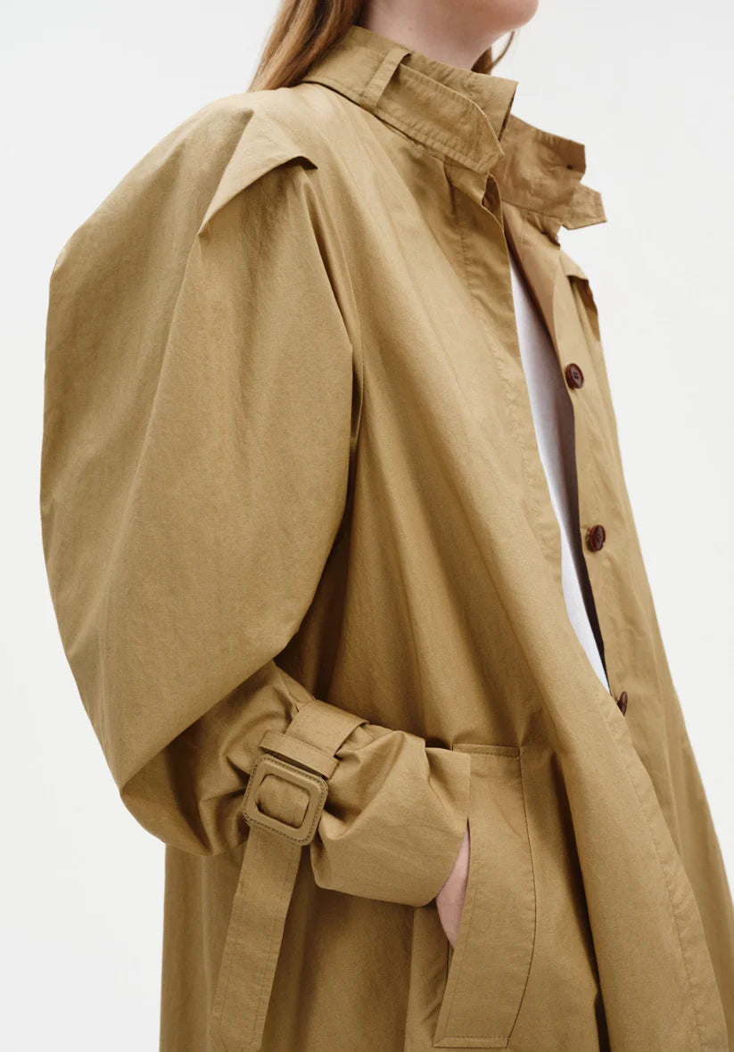 Tan trench coat worn by a person on a white background