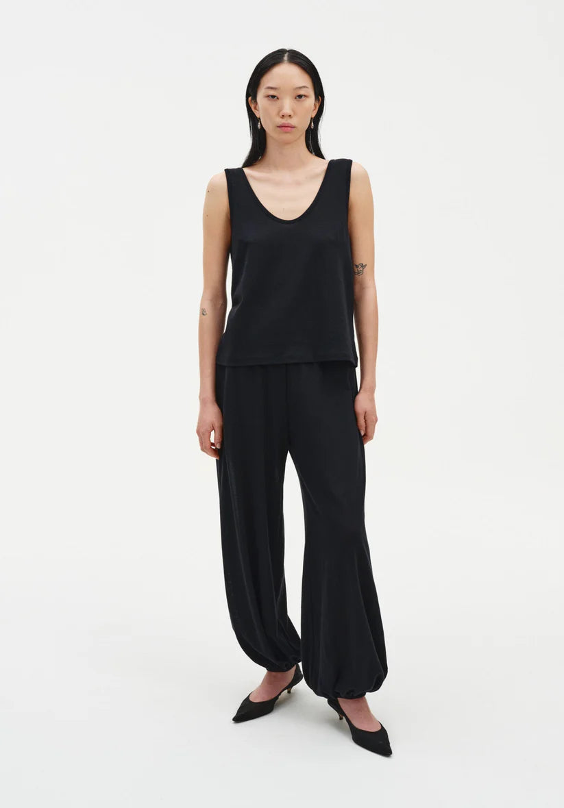Woman wearing a black sleeveless top and wide-leg pants on a white background